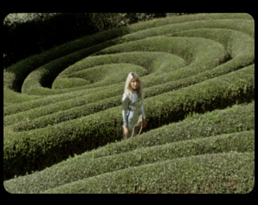 Capture d'écran super 8 d'un labyrinthe où une femme porte une combinaison pailletée.